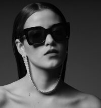 Monochrome fashion portrait by Berlin photographer Bert featuring oversized black Celine sunglasses and a crystal-beaded earring, creating a dramatic, high-contrast eyewear image.