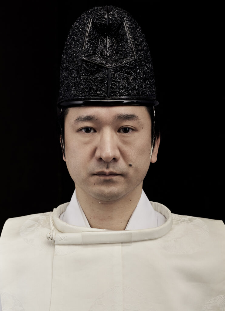 Close-up portrait of Masatsugu Okutani wearing formal Shinto eboshi hat and white robes, photo by Bert Spangemacher