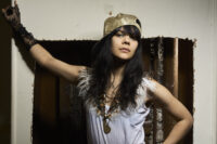 Editorial portrait of Bat for Lashes, Natasha Khan, wearing feathered details and a gold cap, photographed by Bert Spangemacher in New York City.