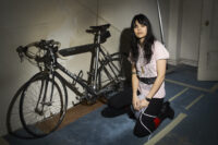 Natasha Khan of Bat for Lashes kneeling beside a vintage TREK bicycle, photographed by Bert Spangemacher in New York City