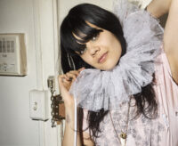 Bat for Lashes (Natasha Khan) in a soft pink outfit and white ruffled collar, photographed indoors in New York City by Bert Spangemacher.